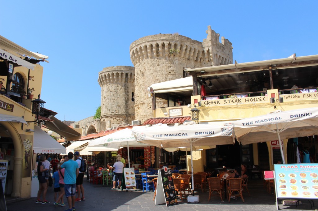 A busy shopping street with a historic background in Rhodes.